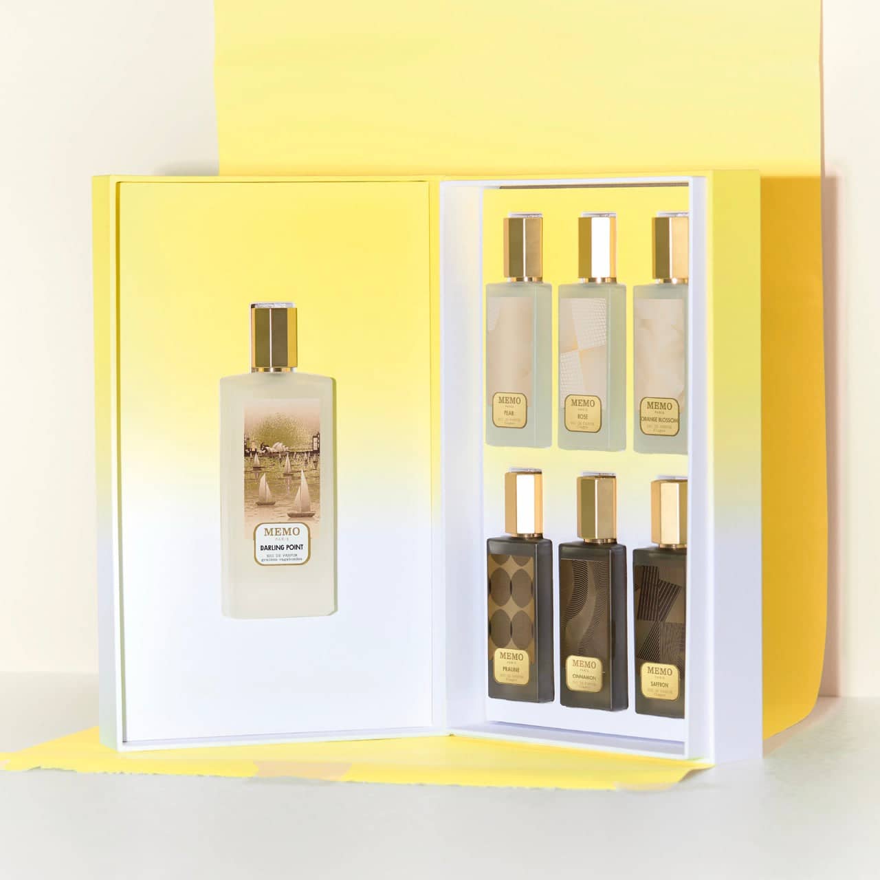Elegant memo paris fragrance set featuring six bottles with gold caps and gradient labels, presented in a sleek yellow gift box.