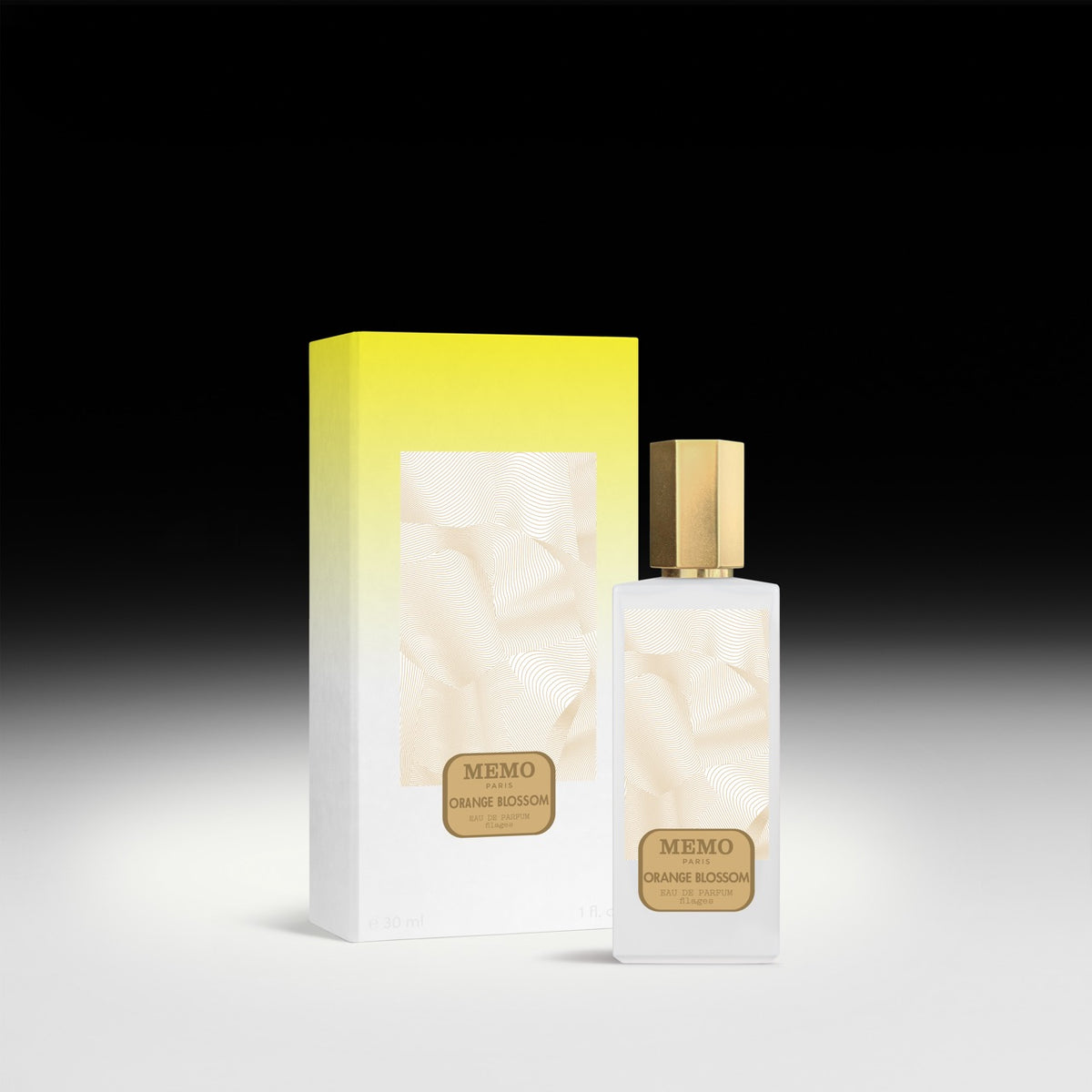 A sleek white glass bottle of memo paris essences filages orange blossom eau de parfum with gold cap beside its box