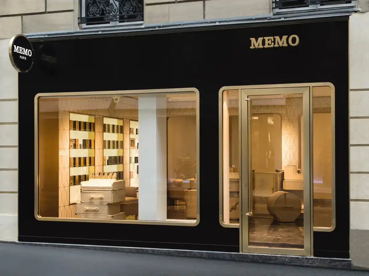 A black storefront with gold trim and lettering, featuring two large display windows and a glass door.