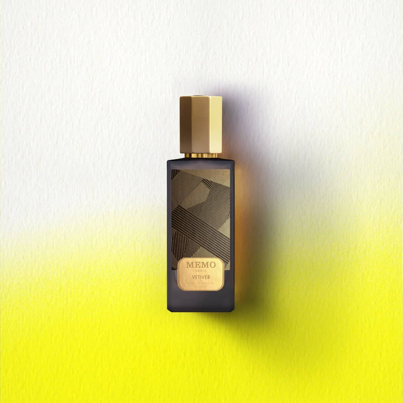 Dark glass perfume bottle with a gold hexagonal cap and label, featuring an abstract geometric pattern in black and gold.