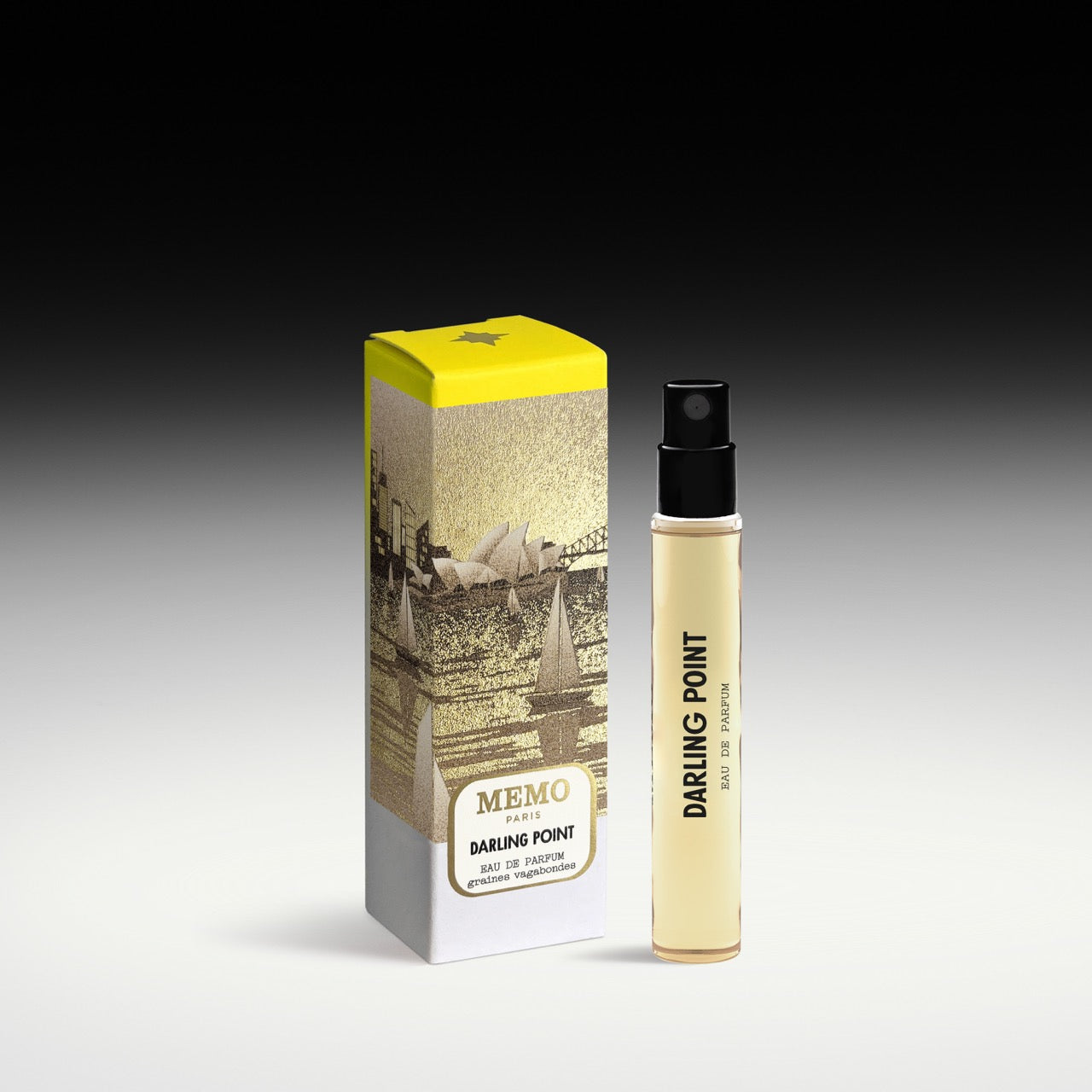 A slender transparent glass bottle of memo paris darling point eau de parfum with pale yellow liquid and black spray nozzle